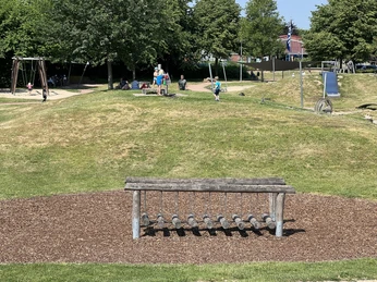 Wassererlebnisspielplatz Bruchhausen-Vilsen Ein lebhafter Wasserspielplatz mit Holzplanken, Schaukeln und spielenden Kindern in einer grünen Umgebung.