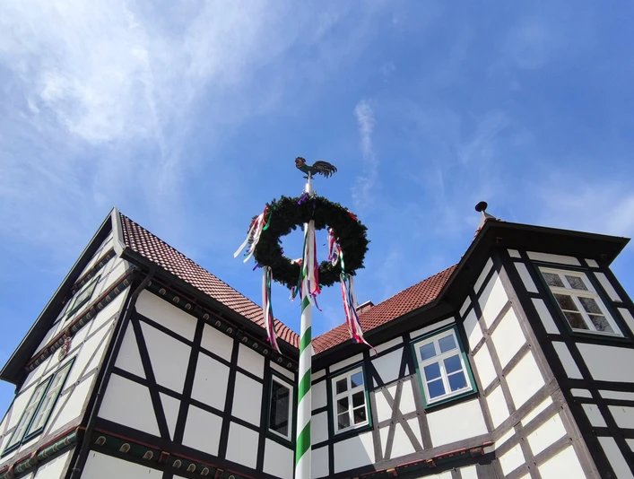 Jagdschloss mit Maibaum Fachwerk-Jagdschloss in Hövelhof mit einem festlich geschmückten Maibaum, der den blauen Himmel ziert.