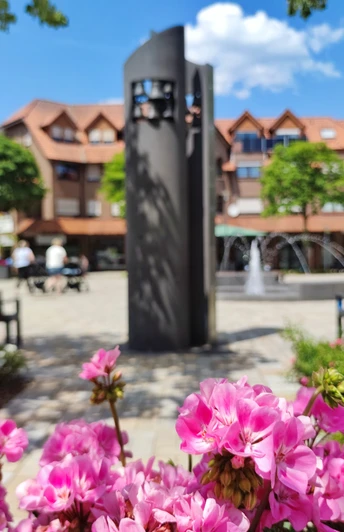 Glockenspiel auf dem Hövelmarktplatz Glockenspiel am Hövelmarktplatz mit blühenden rosa Blumen im Vordergrund und einem modernen Brunnen.