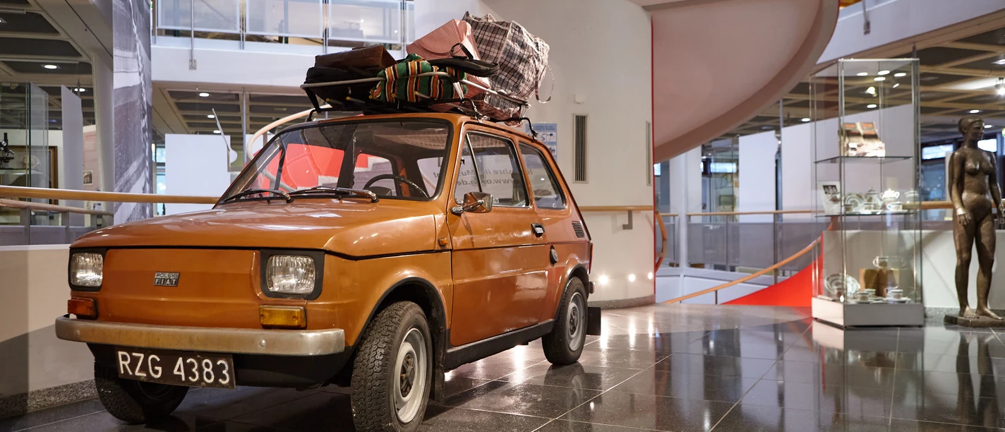 Oberschlesisches Landesmuseum in Ratingen Ein orangefarbenes Auto mit Dachgepäckträger steht im modernen Foyer des Oberschlesischen Landesmuseums.