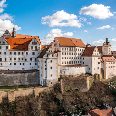 Château de Colditz, impressionnant bâtiment Renaissance sur une colline, entouré de jardins.