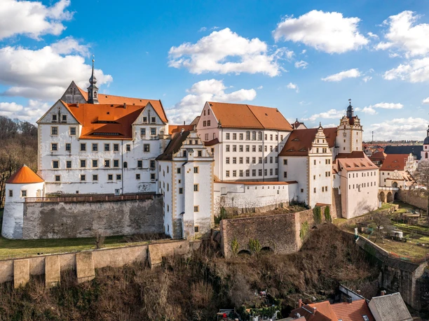 Château de Colditz, impressionnant bâtiment Renaissance sur une colline, entouré de jardins.