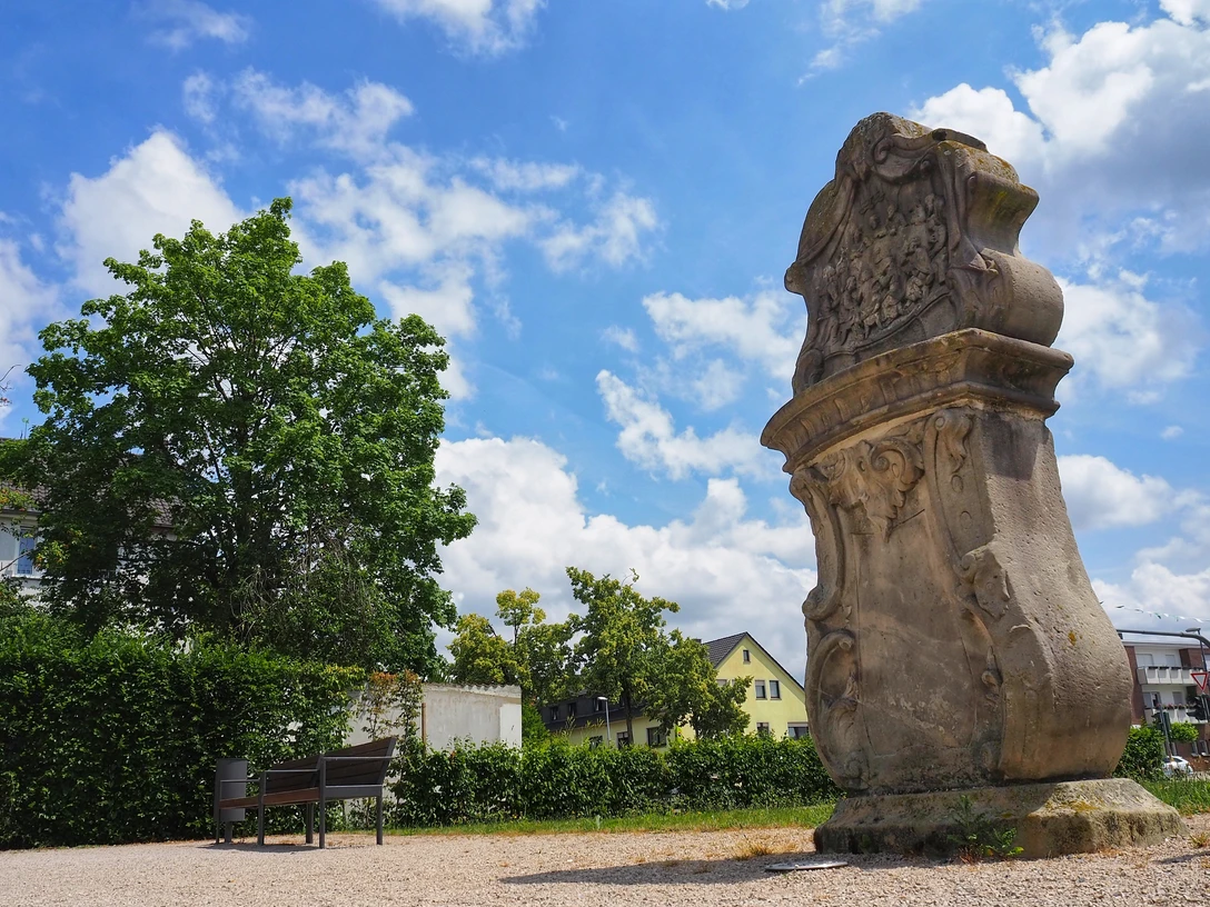 Apostelstein Steinerner Apostelstein mit kunstvollen Gravuren auf einer Grünfläche unter blauem Himmel.