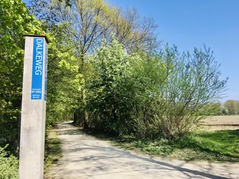 Dalke Wassererlebnispfad (4)-min.JPG Wanderweg Dalkeweg gesäumt von Bäumen unter blauem Himmel im Frühling; Wegweiser zu sehen.