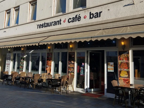 Außenansicht des Restaurants YOL mit Café-Bar-Schriftzug, Markise und Tischen im Freien
