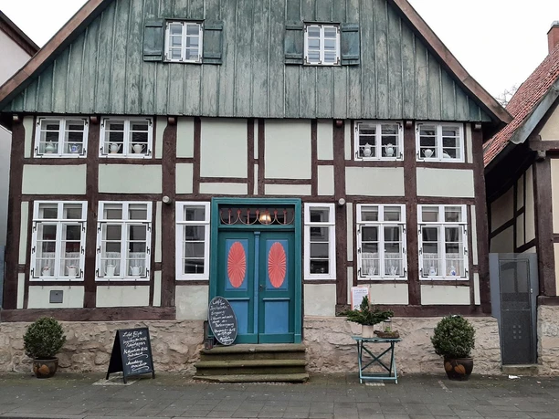 Historisches Fachwerkhaus mit türkis-roter Eingangstür und Tafeln des Cafés am Kirchplatz