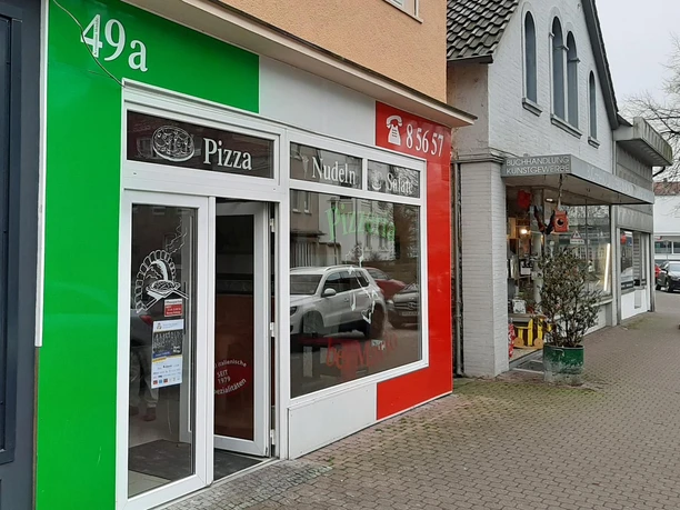 Eingang der Pizzeria bei Mario mit grün-rot gestalteter Fassade und Schaufenstern