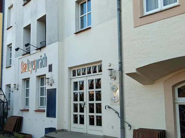 Eingang des Restaurants Stadtgespräch mit heller Fassade und weißen Sprossentüren