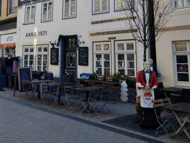 Außenterrasse von Ortmann’s Anno 1966 vor historischer Fassade mit Kellnerfigur