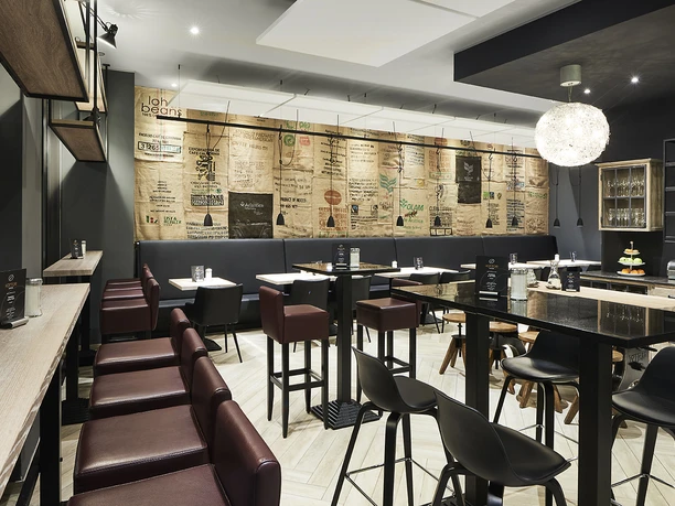 Modernes Café-Interieur mit stilvollen, dunklen Möbeln und beleuchtetem, dekorativem Hängeleuchter.