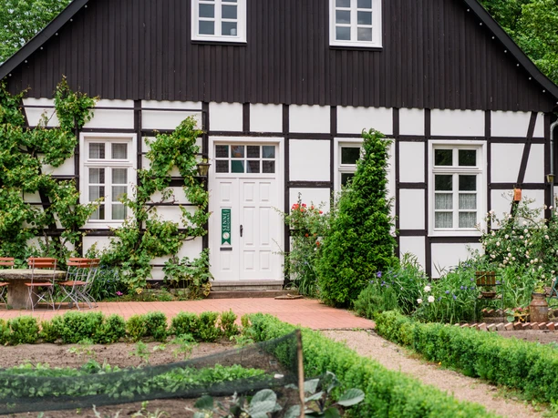Thorsten-Hennig-Fotografie-Fahrradtouren-Hövelhof-2019-A9_06116.jpg Fachwerkhaus mit Pflanzendeko, Garten am Vordergrund, einladende Terrasse mit bunten Stühlen.
