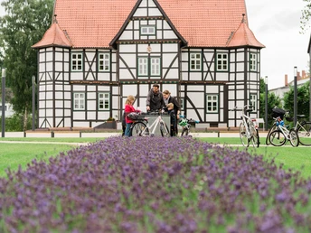 Radfahrergruppe vor Fachwerkhaus in Hövelhof, umgeben von blühenden Lavendelfeldern.