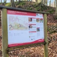 Wanderweg-Tafel im herbstlichen Laubwald des Wiehengebirges bei Eilhausen mit Infokarten.