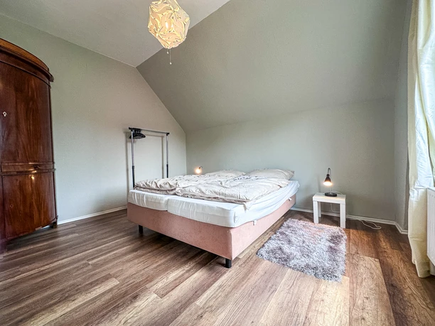 Schlafzimmer Schlafzimmer unter einer Dachschräge mit Doppelbett, antikem Schrank und hellem Holzboden.
