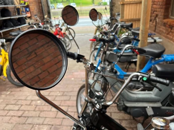 Mehrere abgestellte Mofas stehen eng beieinander in einer überdachten, teils offenen Fläche.