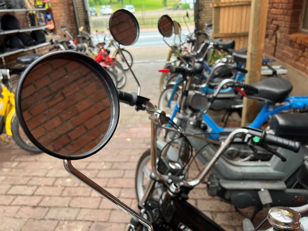 Mehrere abgestellte Mofas stehen eng beieinander in einer überdachten, teils offenen Fläche.