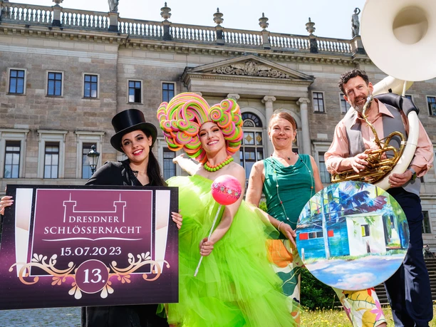 q 2023-06-21_Schornsteinfegerin und Candy Girl von Art of Choice. Beate ....jpg Vier Personen in farbenfrohen Kostümen vor einem Schloss, halten ein "Dresdner Schlössernacht"-Schild.