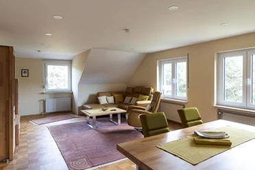 Modernes Wohn-Esszimmer mit gemütlicher Sitzecke, Holzmöbeln und großen Fenstern mit Gartenblick.