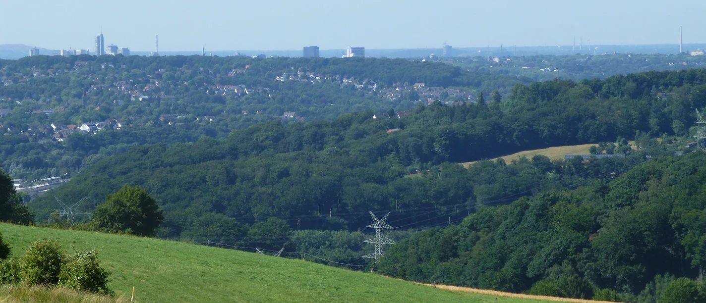 Weitblick auf das Ruhrgebiet Blick auf das Ruhrgebiet mit ausgedehnten Wäldern, Feldern und eine sich am Horizont erstreckende Skyline.