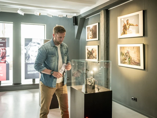 Man looks at shot-up camera by Anja Niedringhaus