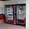 Proviantomat in Gohrisch Zwei rote Verkaufsautomaten stehen nebeneinander; der linke bietet Getränke, der rechte Snacks und Lebensmittel an. Daneben eine rote Kühlbox.Two red vending machines stand next to each other; the one on the left offers drinks, the one on the right snacks and food. Next to it is a red cool box.Dva červené automaty stojí vedle sebe; ten vlevo prodává nápoje, ten vpravo občerstvení a potraviny. Vedle něj stojí červený chladicí box.Dwa czerwone automaty stoją obok siebie; ten po lewej oferuje napoje, a ten po prawej przekąski i jedzenie. Obok znajduje się czerwona lodówka.Twee rode automaten staan naast elkaar; de linker biedt drankjes, de rechter snacks en eten. Ernaast staat een rode koelbox.Due distributori automatici rossi sono uno accanto all'altro; quello a sinistra vende bevande, quello a destra snack e cibo. Accanto ad esso c'è una cassetta termica rossa.