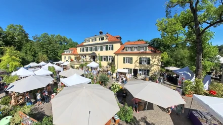 Rosenfest Große, elegante Villa mit roten Dächern umgeben von buntem Markt mit weißen Pavillons und Besuchern.