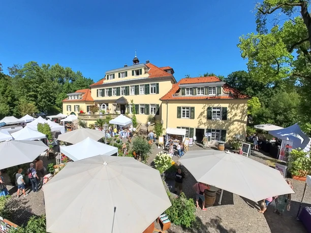 Rosenfest Große, elegante Villa mit roten Dächern umgeben von buntem Markt mit weißen Pavillons und Besuchern.
