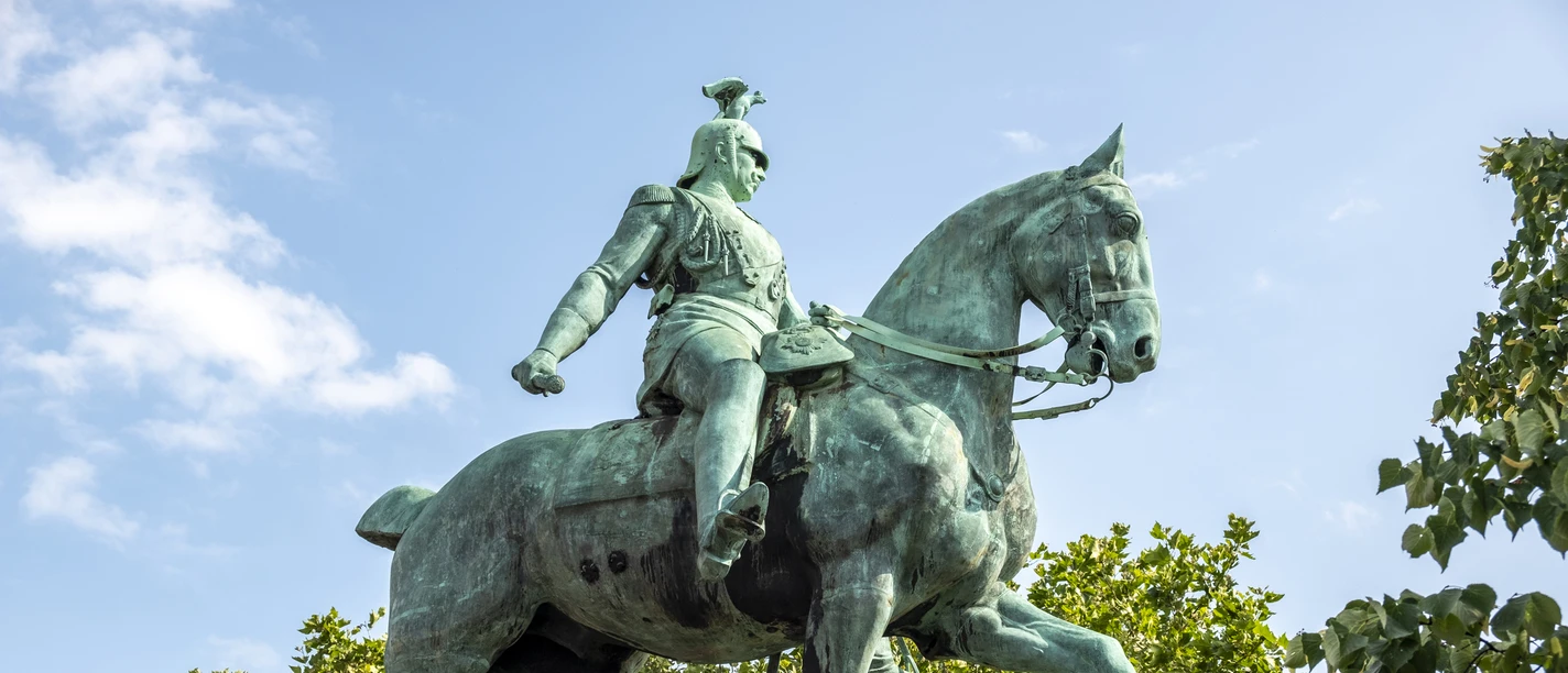 Equestrian statue of King Frederick William III. The picture shows the impressive equestrian statue of Kaiser Wilhelm II in Cologne. Kaiser Wilhelm sits majestically on a powerful horse, surrounded by green trees and a clear blue sky in the background.