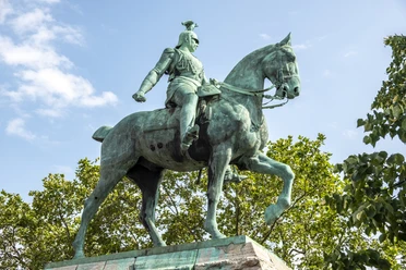 Reiterstandbild König Friedrich Wilhelm III. Das Bild zeigt das beeindruckende Reiterstandbild von Kaiser Wilhelm II. in Köln. Kaiser Wilhelm sitzt majestätisch auf einem kräftigen Pferd, umgeben von grünen Bäumen und einem klaren, blauen Himmel im Hintergrund.
