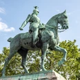 Reiterstandbild König Friedrich Wilhelm III. Das Bild zeigt das beeindruckende Reiterstandbild von Kaiser Wilhelm II. in Köln. Kaiser Wilhelm sitzt majestätisch auf einem kräftigen Pferd, umgeben von grünen Bäumen und einem klaren, blauen Himmel im Hintergrund. The picture shows the impressive equestrian statue of Kaiser Wilhelm II in Cologne. Kaiser Wilhelm sits majestically on a powerful horse, surrounded by green trees and a clear blue sky in the background.