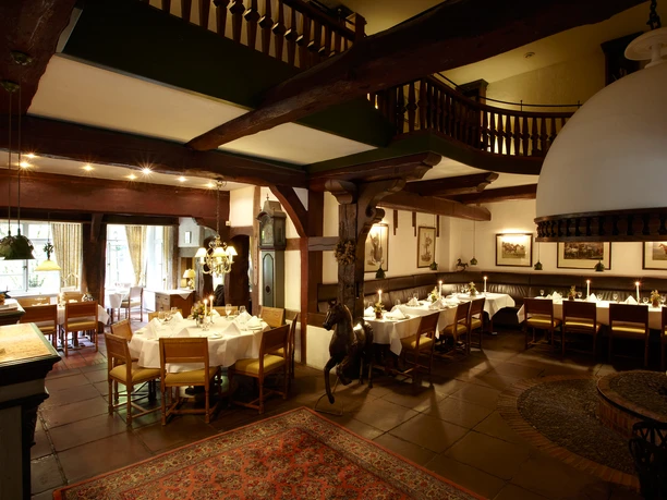 Forsthaus Heiligenberg Rustikales Restaurant mit Holzbalkon, gedeckten Tafeln und einem Kamin im gemütlichen Innenraum.