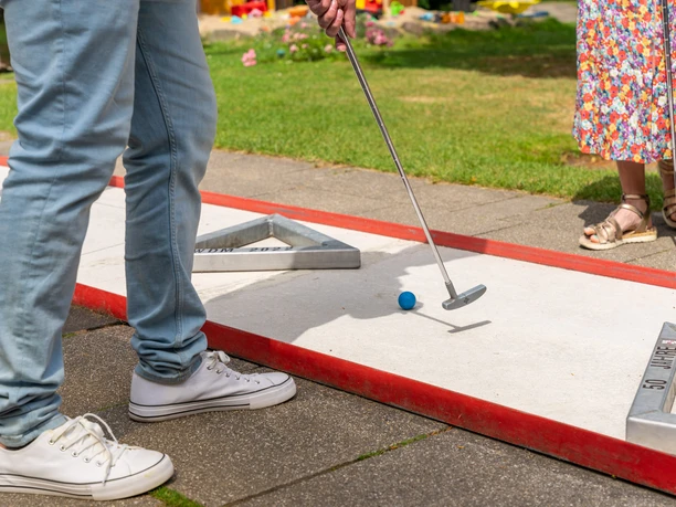 Minigolf-Binder in Velbert-Neviges Zwei Personen spielen Minigolf auf einer gepflegten Anlage, die von saftigem Grün umgeben ist.
