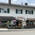Pizzeria Ristorante Vesuvio - Außenansicht Ein Wohnhaus mit einer Pizzeria im Erdgeschoss. Sitzmöglichkeiten vor dem Haus. Bunte Blumenkästen wirken einladend.