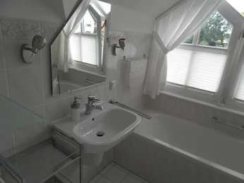 Badezimmer Modernes Badezimmer mit weiß gefliesten Wänden, Waschbecken, Badewanne und einem großen Fenster.