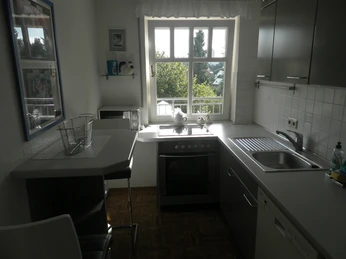 Küche Helle Küche mit großem Fenster, Elektroherd, Spüle, Hängeschränken und gemütlichem Essbereich.