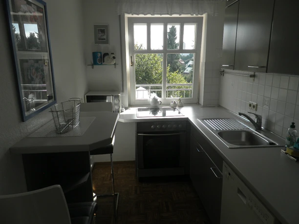 Küche Helle Küche mit großem Fenster, Elektroherd, Spüle, Hängeschränken und gemütlichem Essbereich.