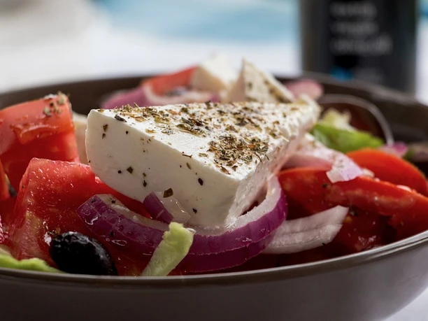 Ein frischer griechischer Salat mit Tomaten, Zwiebeln, Gurken, Oliven und einem großen Stück Feta.