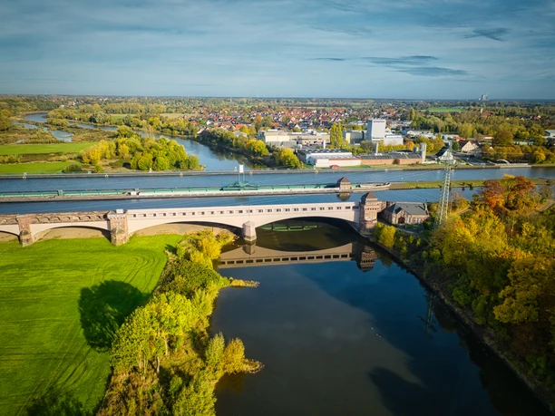 Minden-Wasserstraßenkreuz-Teutoburger-Wald-Tourismus-J-Motzny-030.jpg Luftaufnahme der Schachtschleuse Minden, umgeben von Flusslandschaft und grüner Vegetation im Herbst.