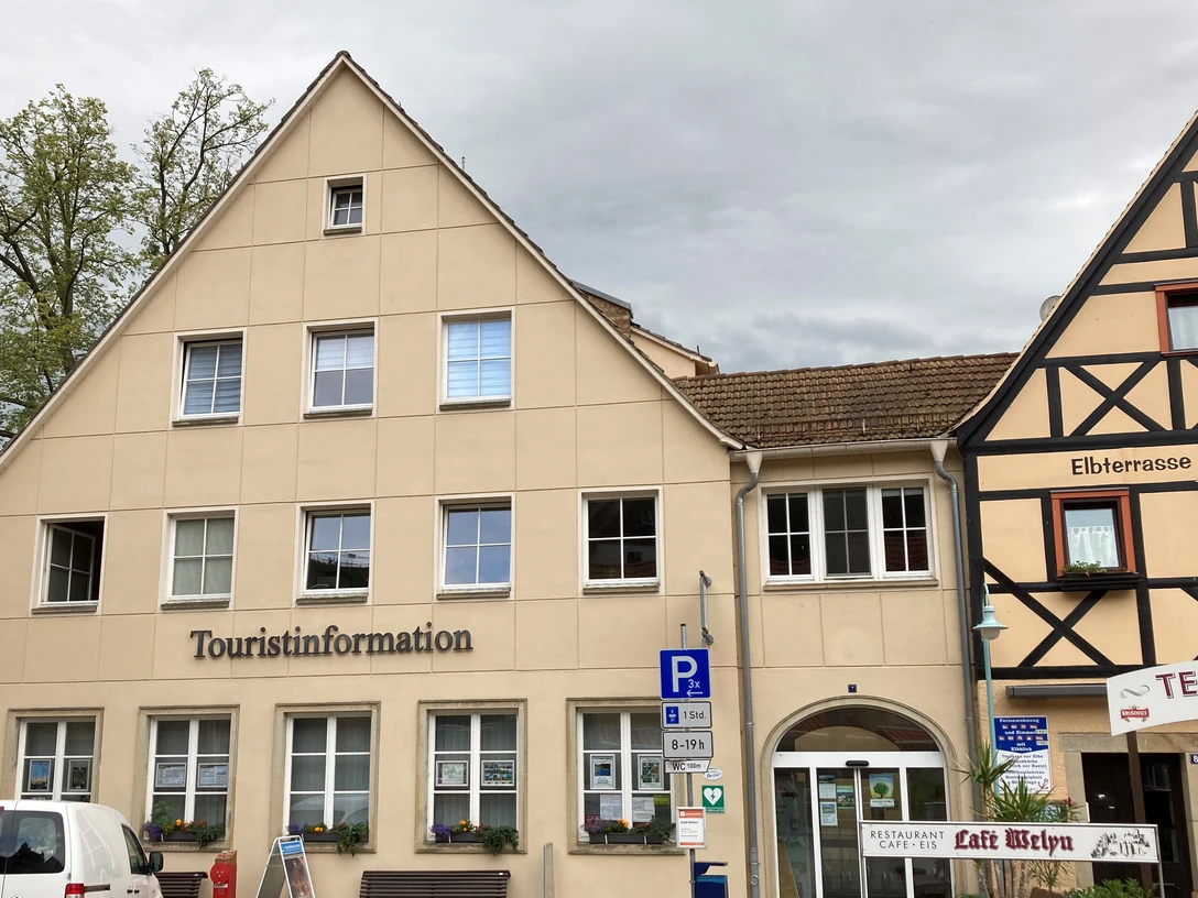Touristinformation am Markt in Stadt Wehlen Zweistöckiges Gebäude mit der Aufschrift "Touristinformation", daneben Fachwerkhaus mit Restaurant "Elbterrasse", bewölkter Himmel.