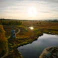 Ein Aussichtsturm im Moorgebiet von Hille bei Sonnenuntergang, umgeben von herbstlicher Natur und Wasserflächen.