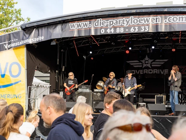 bad-zwischenahner-woche-buehne-marktplatz.jpg Several musicians are playing on stage during Bad Zwischenahn Week, with spectators in front of them.