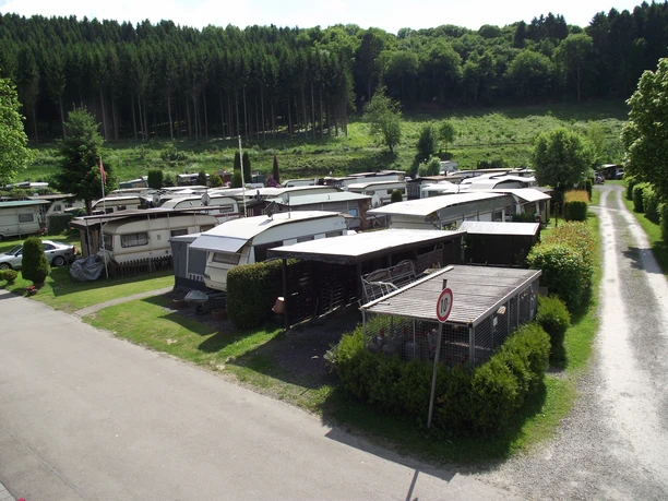 DSCF2705 Kopie_2.jpg Campingplatz mit mehreren Mobilheimen, umgeben von grüner Natur und dichten Wäldern im Hintergrund.