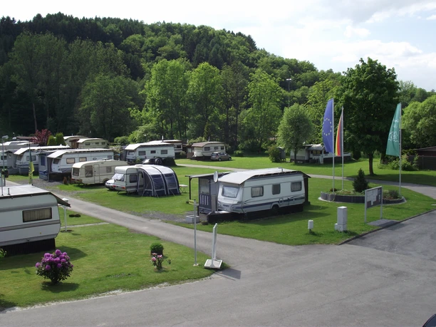 DSCF2704 Kopie.jpg Ein grüner Campingplatz mit Wohnwagen, von Bäumen umgeben, teils sonnig, teils schattig gelegen.