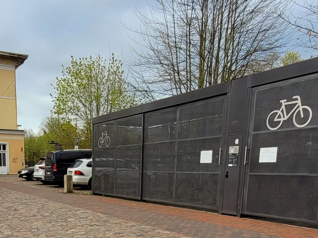 Bahnhof Ratzeburg_Silvana Dust_1980x1080_20230510 (6).jpg Hinteransicht Bahnhofsgebäude Ratzeburg mit Parkplätzen für Autos und Fahrräder
