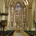 Gotische Kathedrale in Osnabrück mit beeindruckenden Buntglasfenstern und reihenweise Sitzbänken.