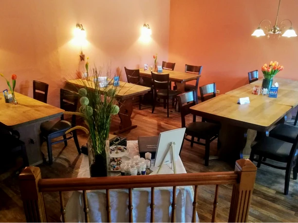 Gasthaus Görtmöller Einladender Gastraum mit Holztischen, frischen Blumen und warmen Farbtönen in einem Gasthaus.