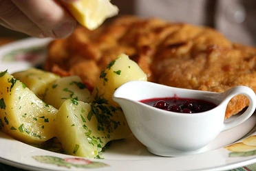 Gasthaus Görtmöller Ein Teller mit Petersilienkartoffeln, Schnitzel und einer Schale mit Preiselbeersauce.