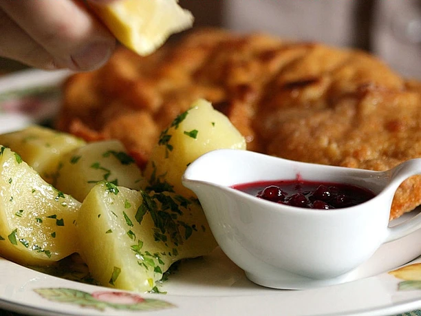 Gasthaus Görtmöller Ein Teller mit Petersilienkartoffeln, Schnitzel und einer Schale mit Preiselbeersauce.