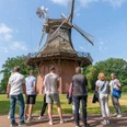 mühle.jpg Eine Gruppe von Menschen betrachtet eine historische Windmühle bei sonnigem Wetter im Grünen.A group of people look at a historic windmill in the countryside on a sunny day.En gruppe mennesker ser på en historisk vindmølle på landet på en solrig dag.Een groep mensen bekijkt een historische windmolen op het platteland op een zonnige dag.