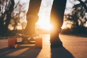 Pexels pixabay.jpg Silhouette eines Skateboardfahrers auf einem Weg bei Sonnenuntergang, leuchtendes Licht im Hintergrund.